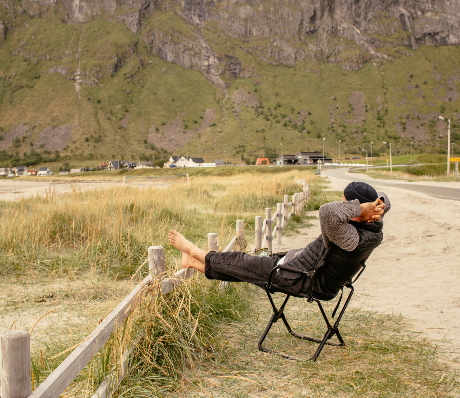 Sascha sitzt in einem Campingstuhl und beobachtet das Meer am Strand in Norwegen. 